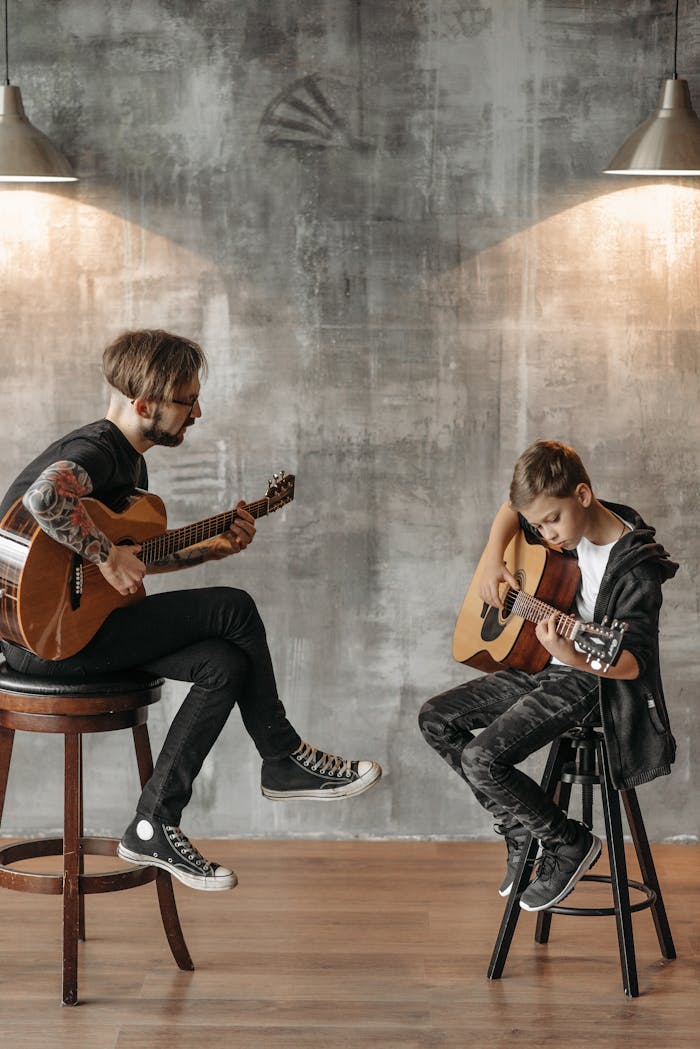 A Tattooed Man and a Young Boy Playing Guitar Together